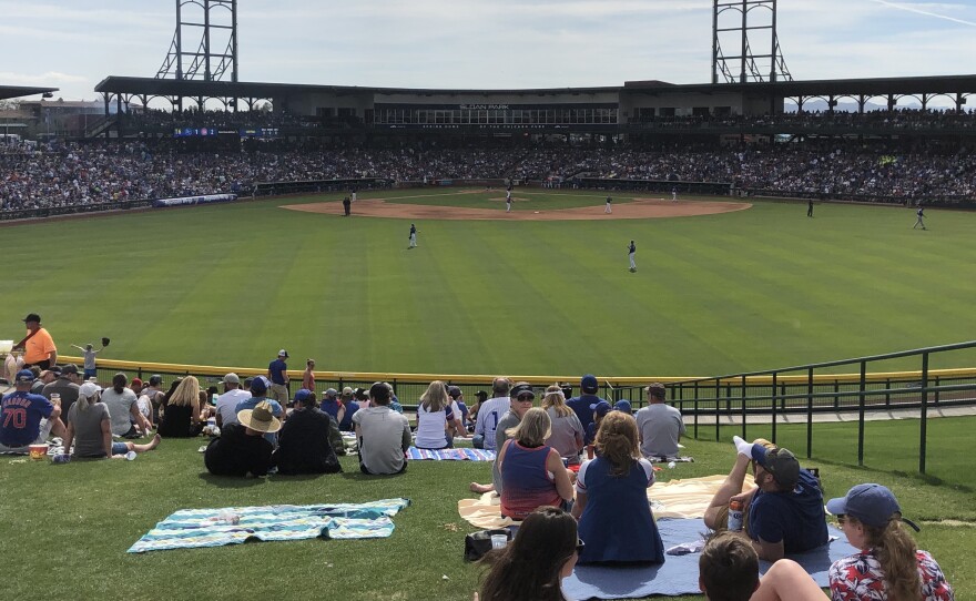 Baseball fans lounge on blankets beyond the center field wall at Sloan Park, the spring training home of the Chicago Cubs, in Mesa, Ariz.
