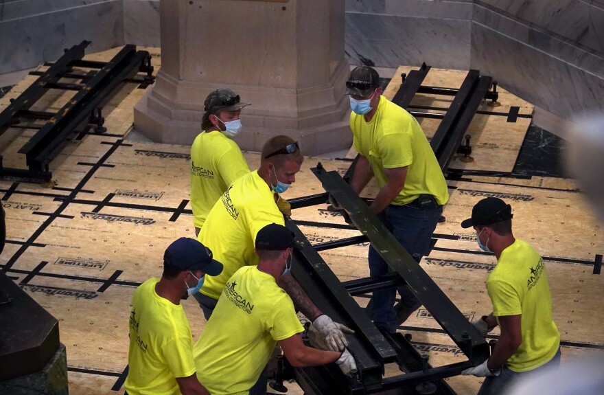 A crew of more than a dozen men lay metal rails during the deinstallation process of the Davis statue at the State Capitol on June 12, 2020.