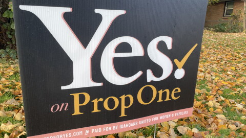 A close up of a political yard sign promoting the prop 1 ballot initiative, on a lawn strewn with fall leaves