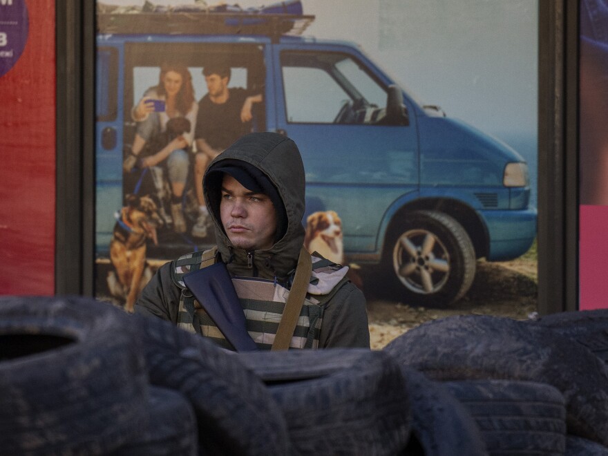 A civil defense man stands guard at a checkpoint in Kyiv, Ukraine, Saturday, as Russian troops continued their advance.