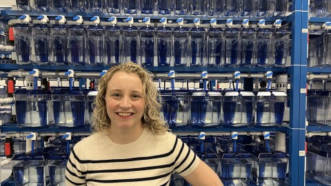 A woman poses in front of fish tanks.