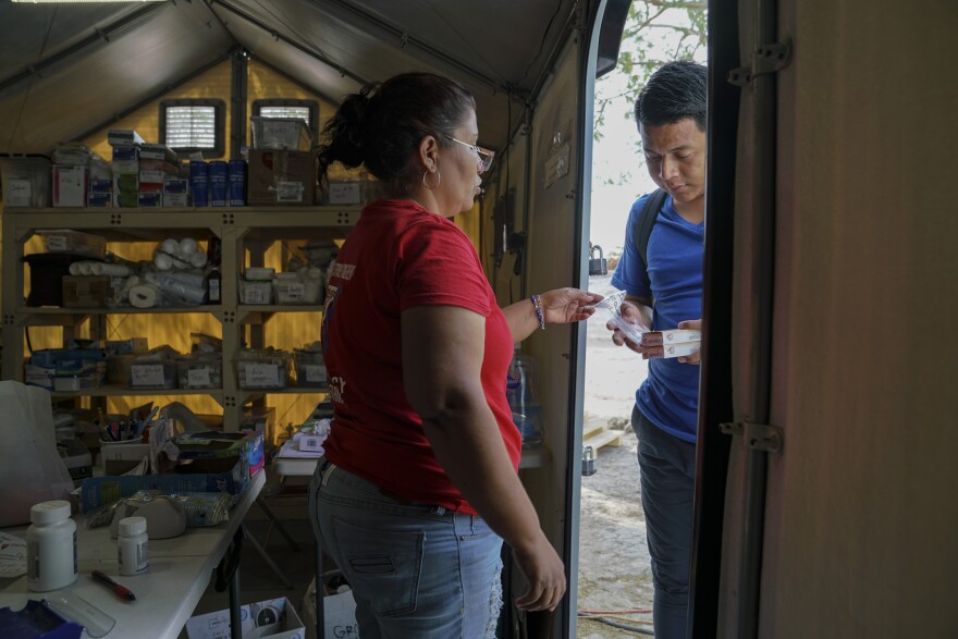 Perla, an asylum-seeker who works at the Global Response Management clinic gives a patient his medication in a migrant camp in Matamoros, Mexico on March 17, 2020.