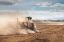A tractor is plowing very dry and dusty farm land in a drought