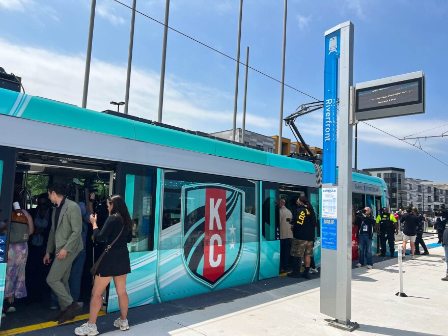 People board a streetcar with a KC Current-branded wrap