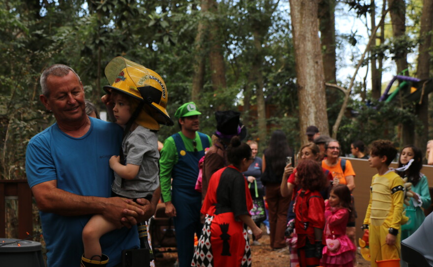 A man holds a boy dressed as a firefighter as they make their way through Boo at the Zoo on Wednesday, Oct. 28, 2026. (David Caine/WUFT News)