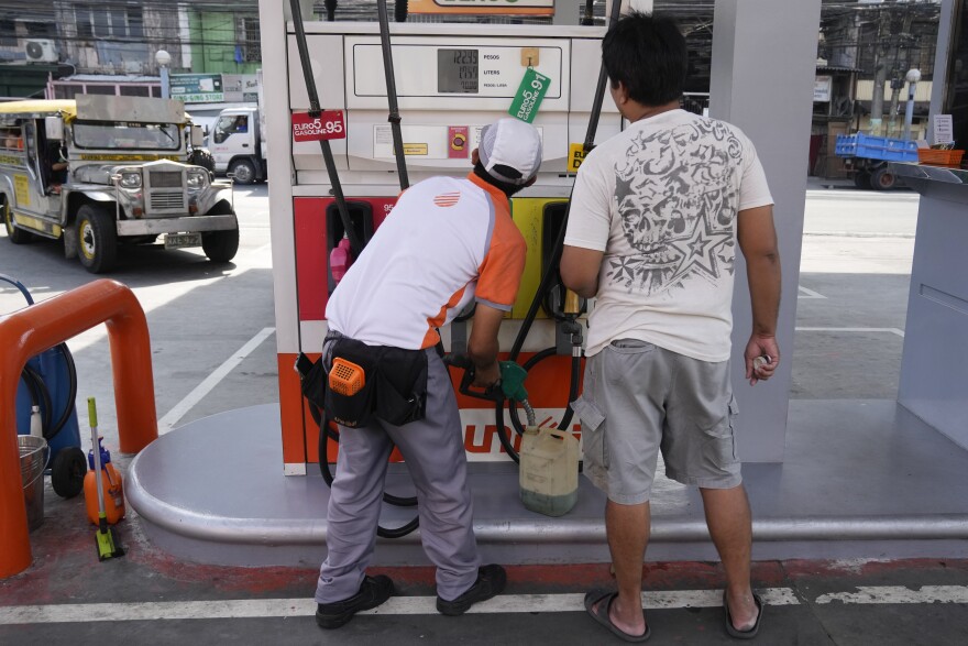 A worker fills up a plastic container with gasoline at a gas station in Pasay, Philippines on Tuesday, Oct. 11, 2022. (AP Photo/Aaron Favila)