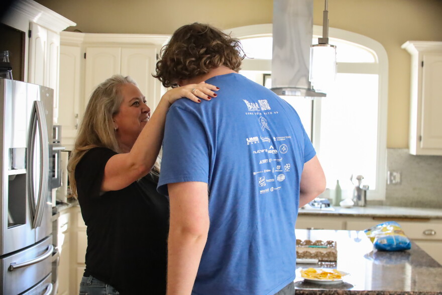Anne Hayes hugs her son in their kitchen in Overland Park, Kansas, on October 5, 2026. Hayes’ son is autistic and stands at over six feet tall. Hayes says her son's size makes it difficult to control his outbursts.
