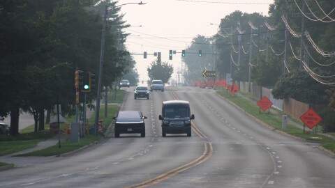 Cars move down a road on a hazy sunny morning