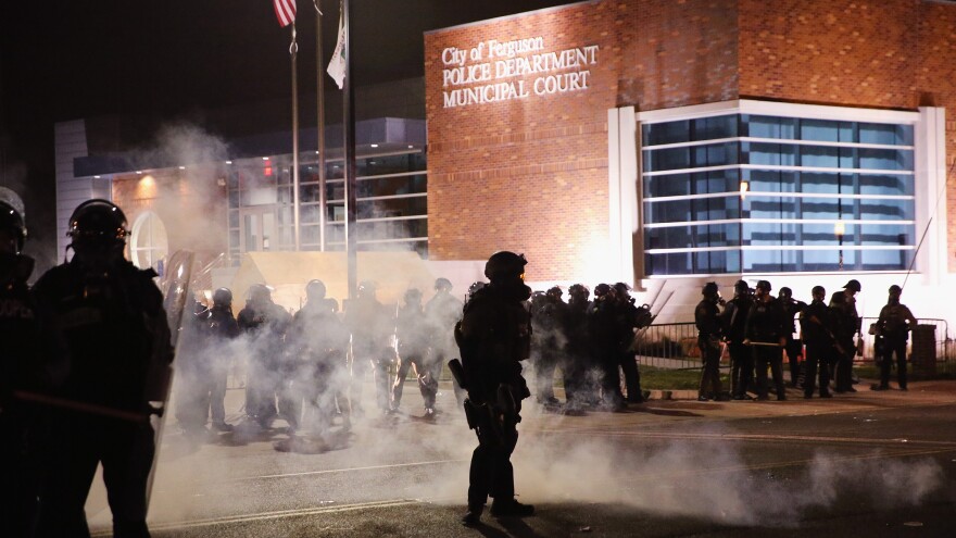 Police guard the Ferguson police department as rioting erupts following the grand jury announcement in the Michael Brown case on Monday in Ferguson, Mo.