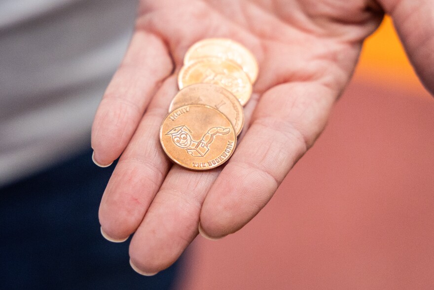 Bluebonnet Elementary Librarian Pattie Nix shows golden tokens with a bookworm engraving that are used to get a book from the book vending machine.