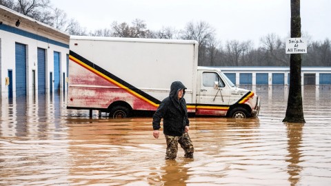 Dekoda Cruz walks through flood water while helping a friend who’s tire shop flooded during heavy rains on Monday, Dec. 22, 2025, in Redding, Calif.