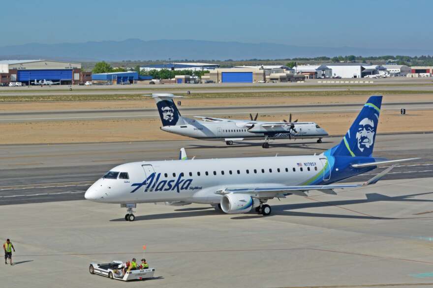 A white and blue Alaska Airlines plane sits on the tarmac. 