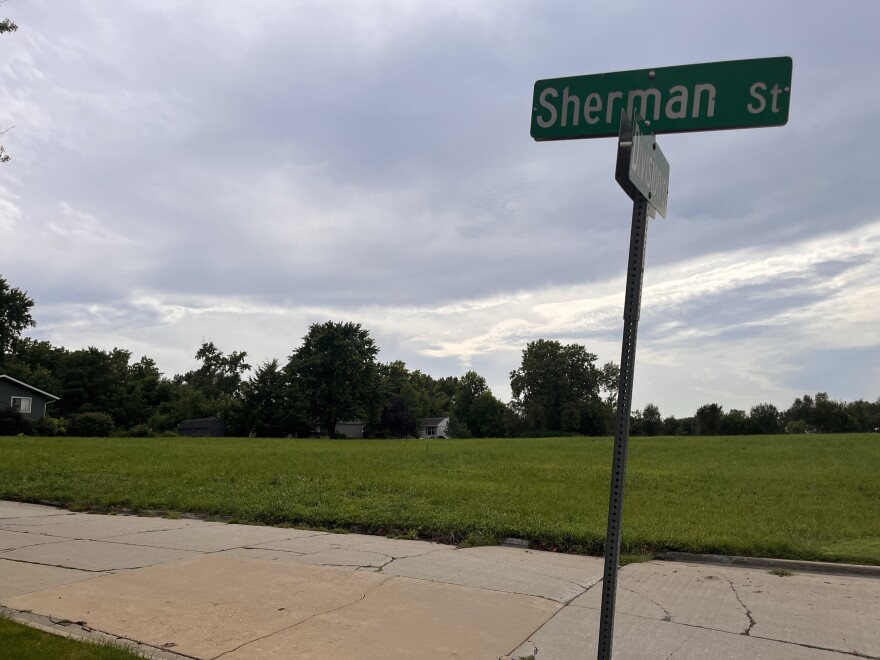 an open plot of land in the background. In the foreground is a sign for Sherman Street