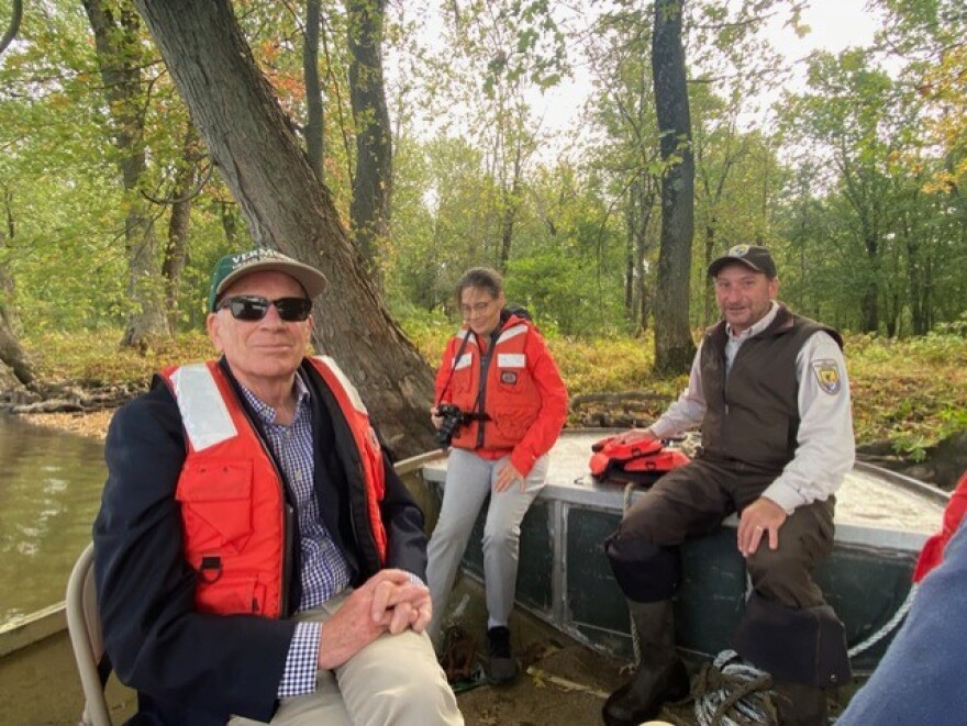 Sen. Peter Welch sits in a boat wearing sunglasses with the Missisquoi national wildlife refuge manager and a woman.