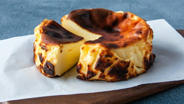 A traditional burnt Basque cheesecake on a wooden cutting board