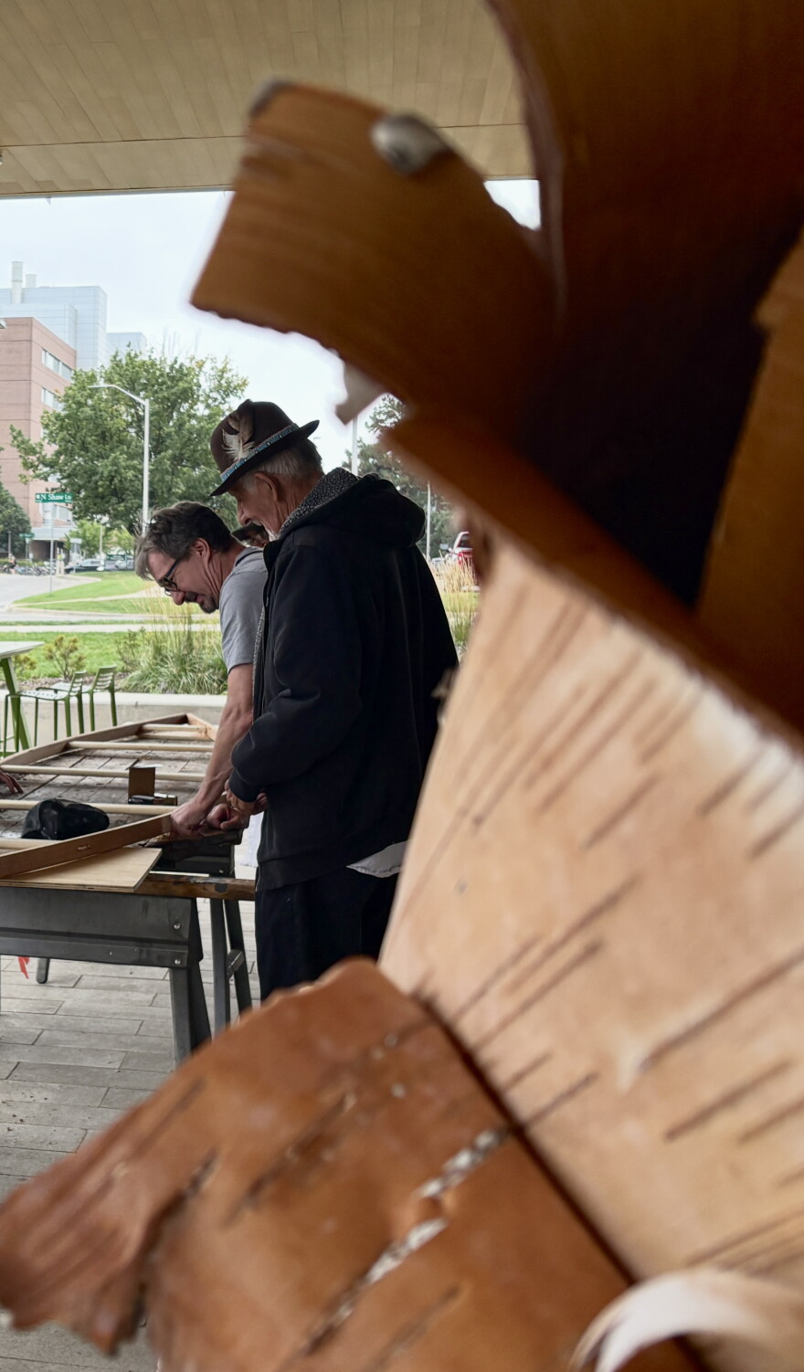 Ron J. Paquin framed by birch looking over the canoe build