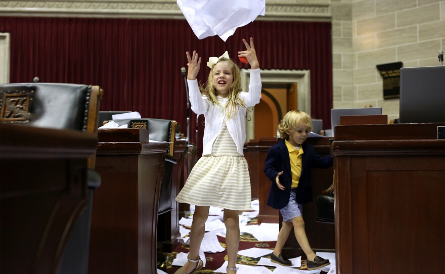 Margaux Harris, 7, granddaughter of Rep. Mike Lair, throws papers in the air shortly after members of the House did the same to mark the end of the legislative session.