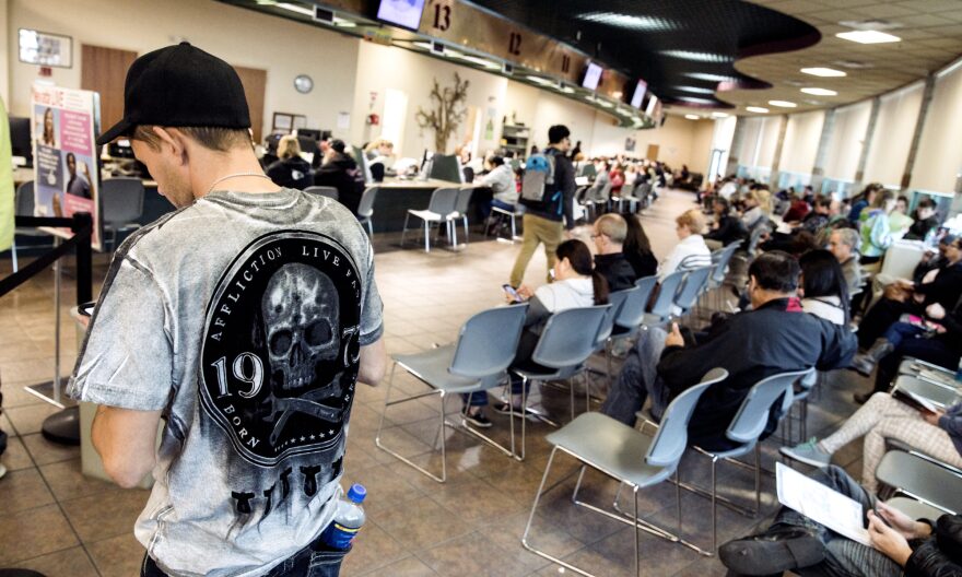 People standing and sitting in a DMV office.