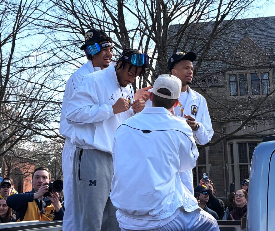 Players Yaxel Lendeborg, Roddy Gale Jr., Trey McKenney, and Charlie May at the parade, riding in a white vehicle.