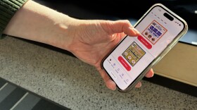 A hand holds a phone displaying digital lottery games