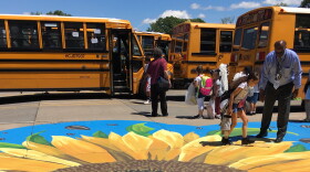 Staffer help students onto school buses outside of John James Audubon School #33 on Webster Avenue during June 2019.