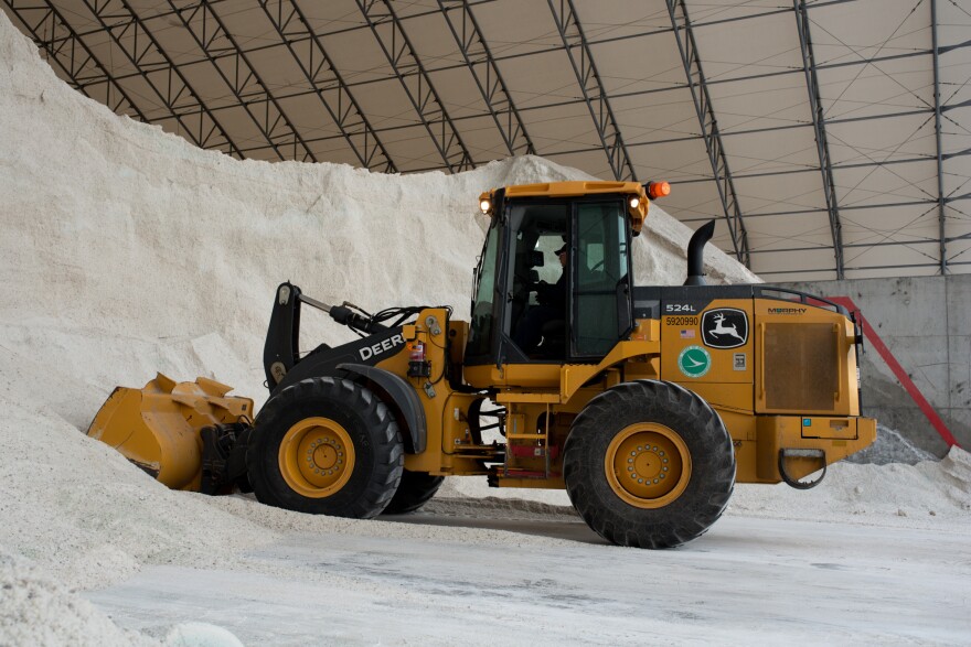An ODOT loader digs into a pile of salt to fill dump trucks.