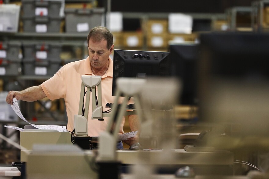 An employees at the Palm Beach County Supervisor of Elections office feed ballots through a machine
