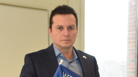  Dmitry Burshteyn, associate professor of psychology at Siena College, holds an "We Stand with Ukraine" flag. 