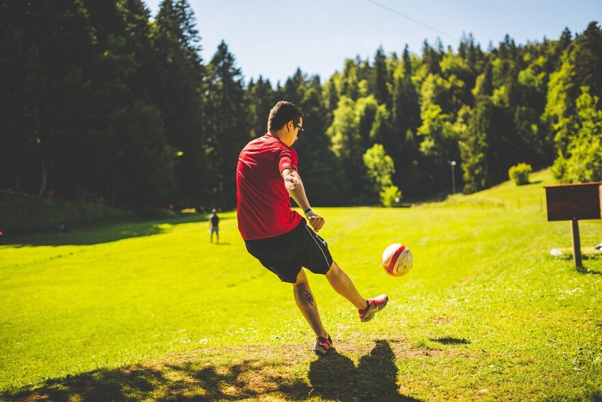  A man kicks a soccer ball in a park.