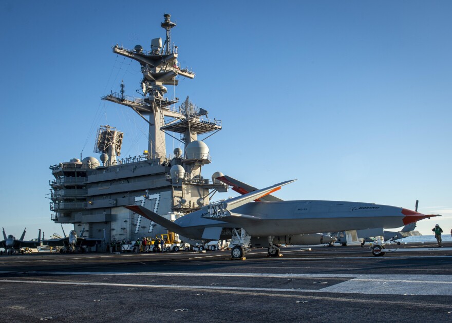 A Boeing unmanned MQ-25 aircraft is given operating directions on the flight deck aboard the aircraft carrier USS George H.W. Bush.