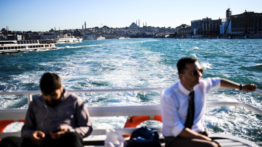 People travel on the Bosphorus by ferry through Istanbul on Wednesday. A bloom of phytoplankton has turned the strait bright turquoise.