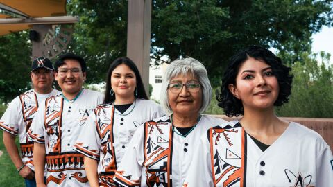 Marvis Vallo, Collin Magdalena, Paris Wise, Patsy Him, and Brittney Juancho model the special jerseys, which draw inspiration from San Ildefonso, Cochiti, and other Pueblo traditional styles. The Albuquerque Isotopes will wear the jerseys and caps on Saturday, Aug. 8.