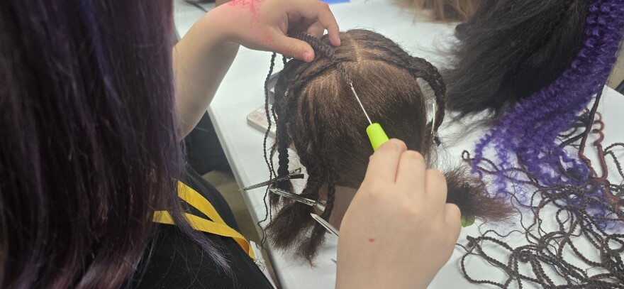 Student crocheting hair into the mannequin head.