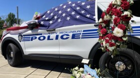 makeshift memorial is growing outside the police station on North Tryon Street, where Eyer’s patrol car driven is draped with an American flag and covered with flowers and cards.