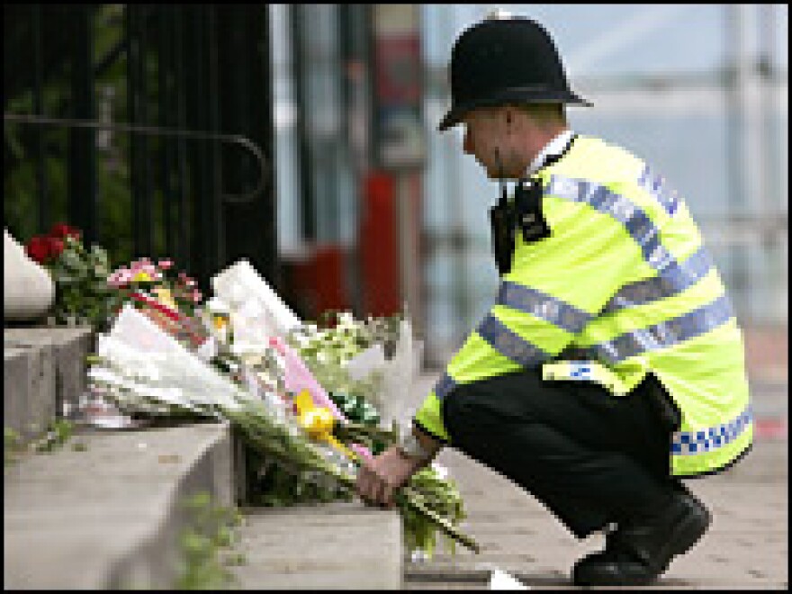 A police officer lays flowers, handed to him by people not allowed to access part of Tavistock square in London, days after the July 7 attacks.