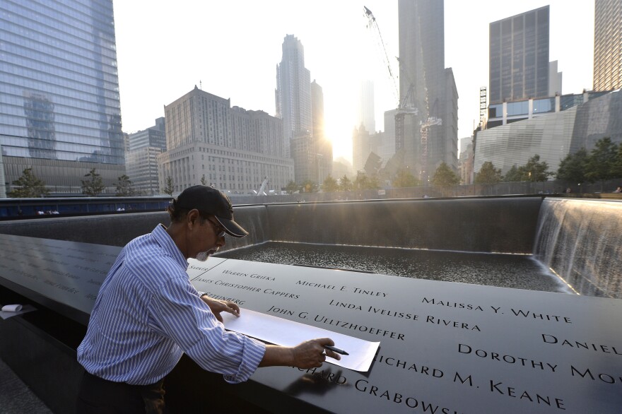 Wakiley Ramen Chowdhury makes a rubbing of his niece's name, Shakila Yasmin, at the edge of the North Pool at the 9/11 Memorial.