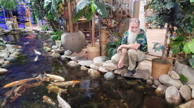 Rick Preuss smiles while kneeling over the pong in his store