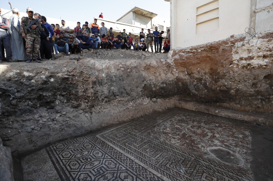People look at a large mosaic that dates back to the Roman era in the town of Rastan, Syria, on Wednesday.