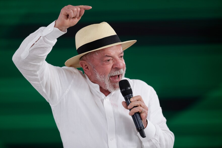 Man in a Panama hat holds a microphone and raises his hand in the air 