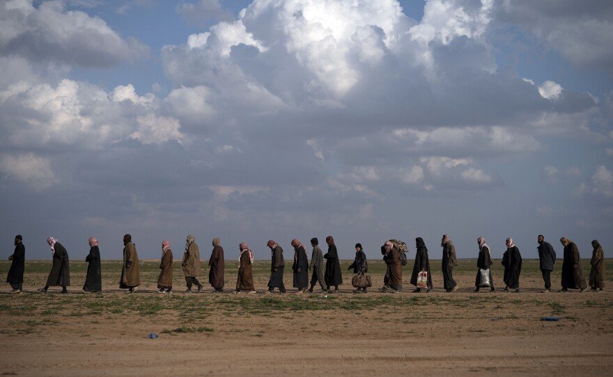 Men walk to be screened by the SDF near Baghouz, eastern Syria, Feb. 22.