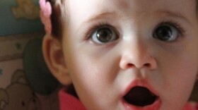 Human baby Charlotte, the 13-month-old daughter of NPR producer Tom Bullock, tried the same tests that DeeChee, the robot, does for language-learning experiments. Dr. Caroline Lyons says human babies have an advantage: They spend every waking hour of the day in a speaking world.