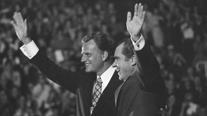 The late preacher Billy Graham, left, and President Richard Nixon wave to a crowd of 12,500 in 1971 in Charlotte, N.C., at an event honoring Graham.