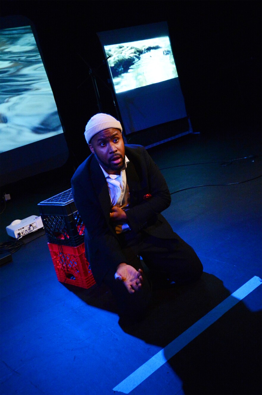 A man acting on stage in a dark theater