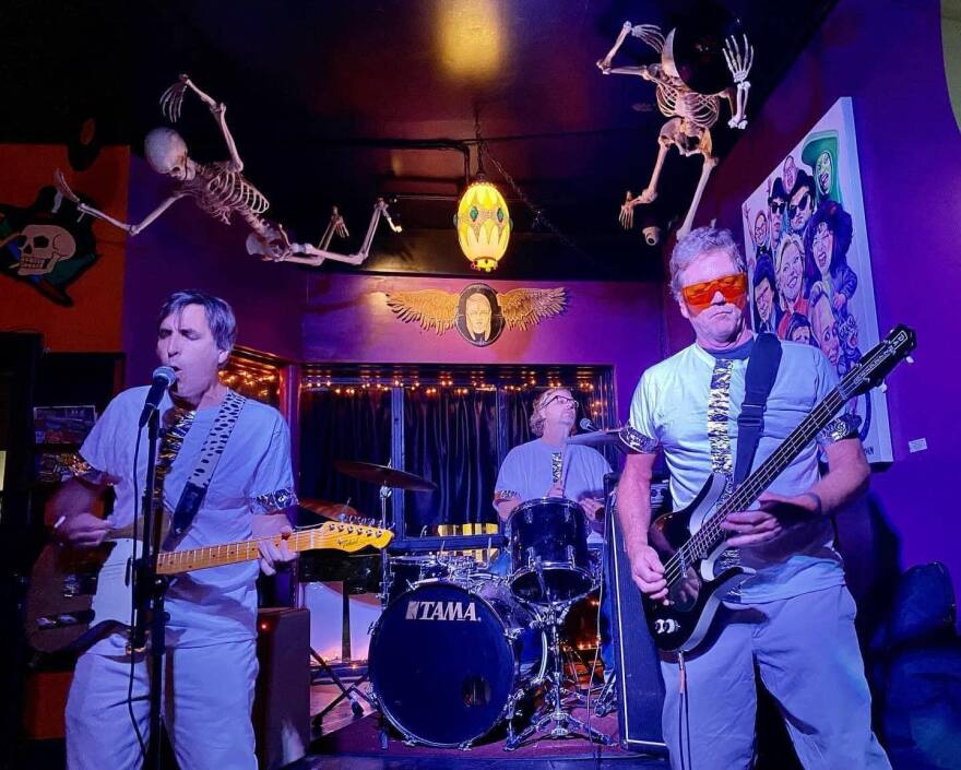 Nod band members playing in a spooky venue with skeletons hanging from the roof above.