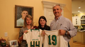 In front of Tripp's photo his mother Sandra, sister Emily and father Glenn Rabon hold his baseball and football jersey. Tripp was killed in a car crash in December 2015. 