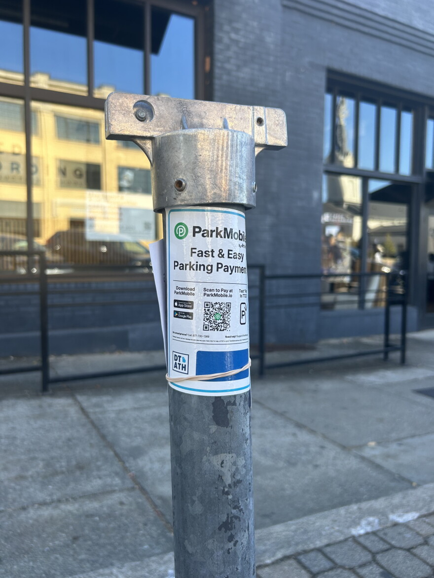 A parking meter pole downtown, missing its aluminum zone number sign.
