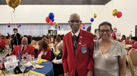 Daniel Keel, a 104-year-old Tuskegee veteran, poses with his daughter. He wears a red blazer. 