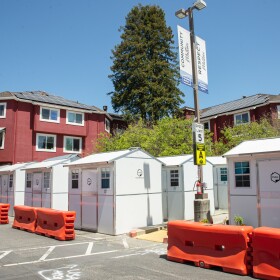 Rows of pallet shelters — 64-square-foot portable structures with lockable doors, outlets for chargers, heating, windows, and beds — at the Housing Matters campus on Coral Street in Santa Cruz.