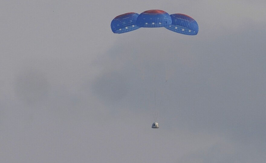 Blue Origin's New Shepard capsule parachutes down to the launch area following its flight into space on Tuesday.