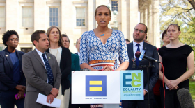 photo of Candis Cox speaking at a podium with signs for the human rights campaign and equality NC